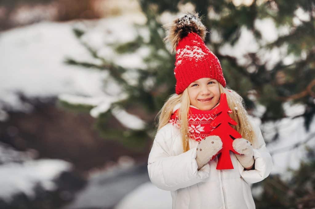a little girl with a red Christmas tree in her hands in winter on the street.girl with a Christmas