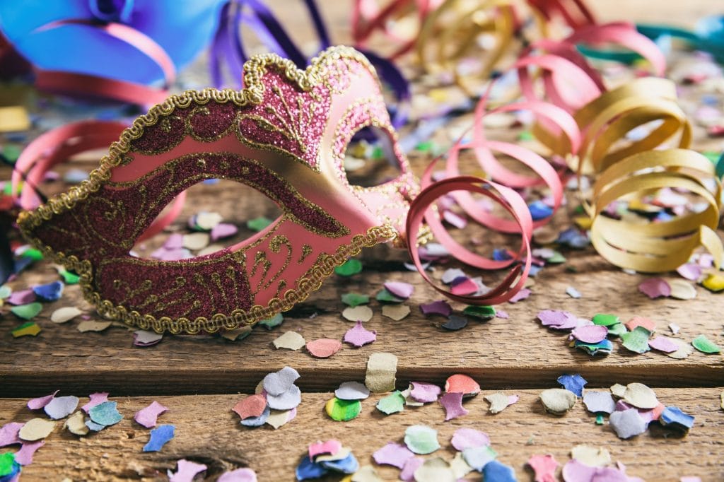 Carnival party. Mask, confetti and serpentines on wooden background